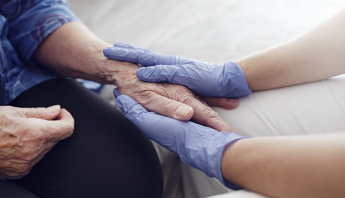 gloved hands holding nursing home residents hand